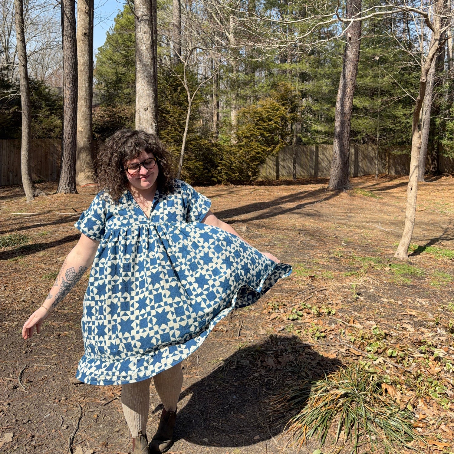 Person in a blue patterned dress standing on a path with trees in the background
